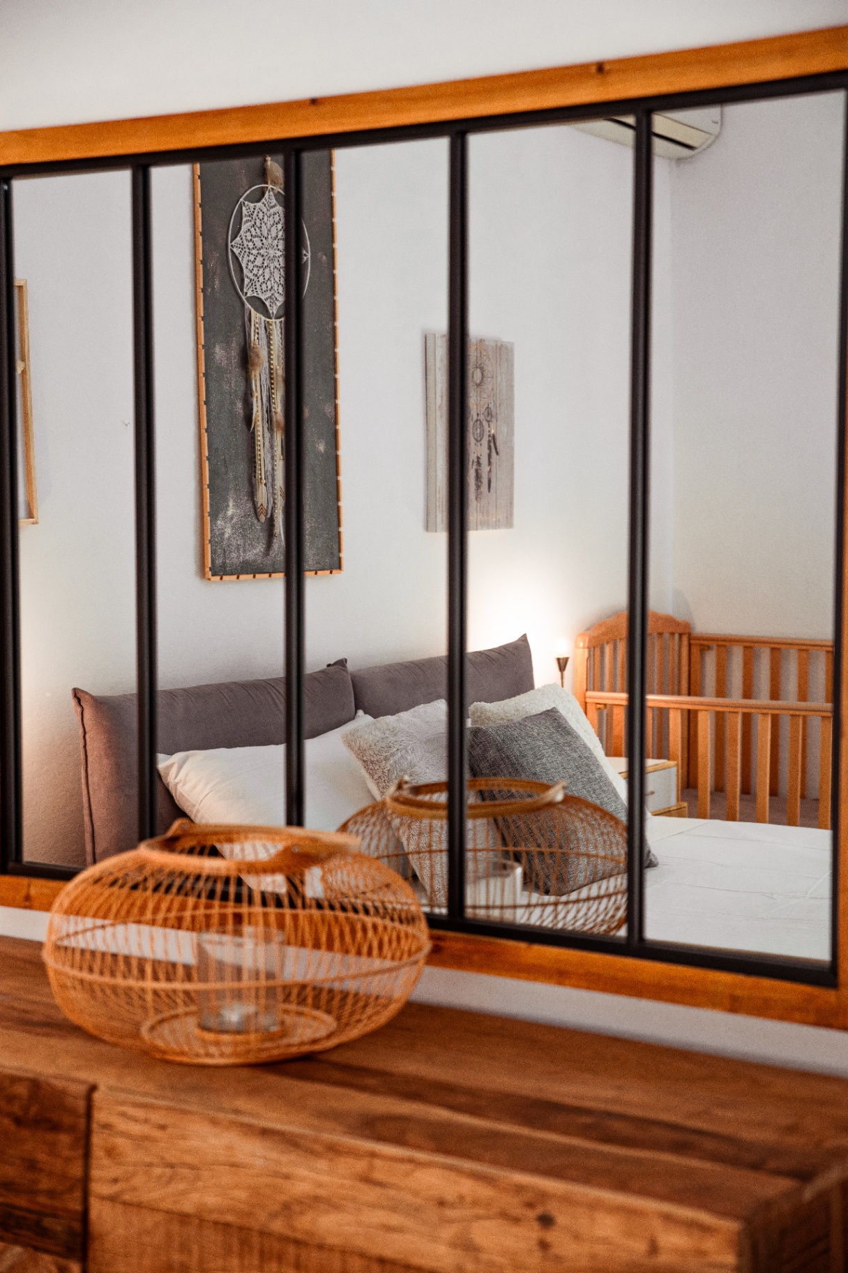 Verrière intérieure en bois et acier reflétant la chambre principale