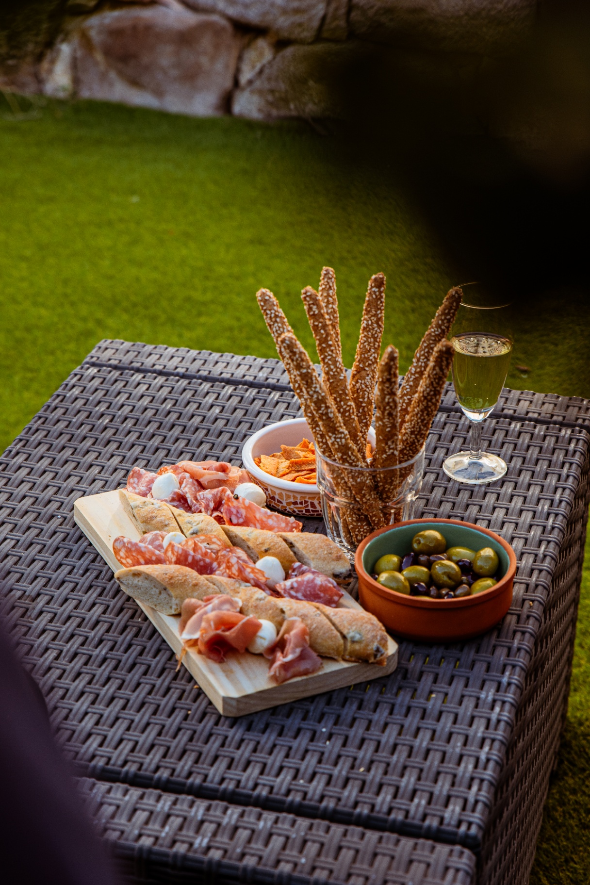 Planche de charcuterie, olives et grissini au sésame servis au jardin
