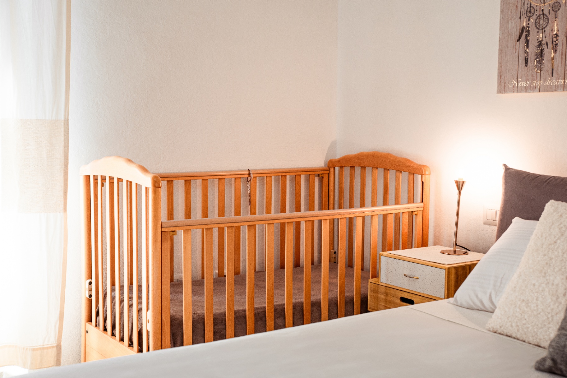 Coin nuit : lit bébé, chevet vintage et liseuse en laiton