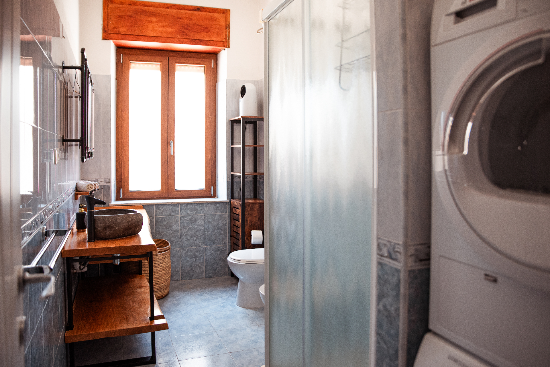 Vue d'ensemble de la salle de bain : douche, WC et espace buanderie