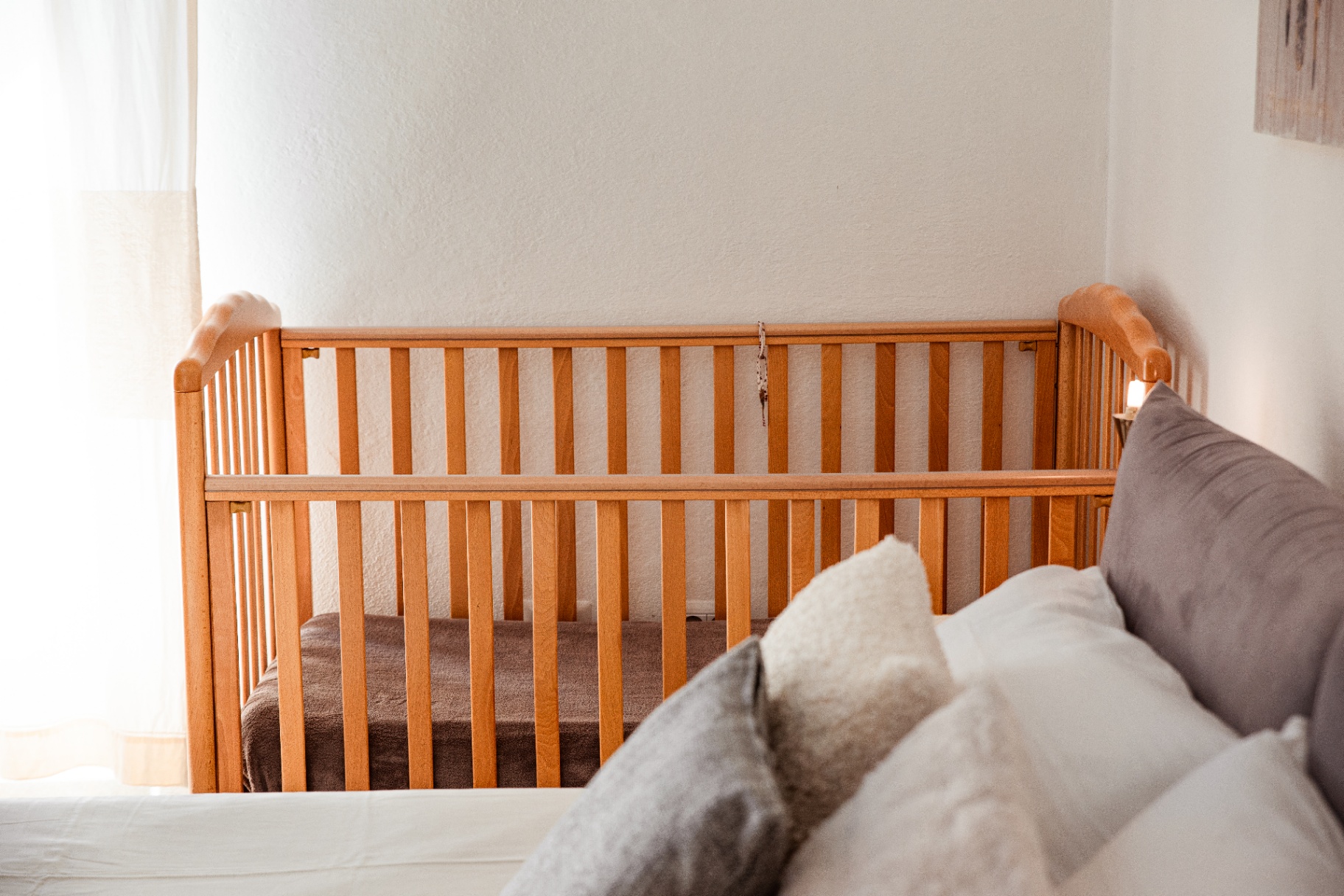 Détail du couchage : lin blanc, plaids et coussins texturés