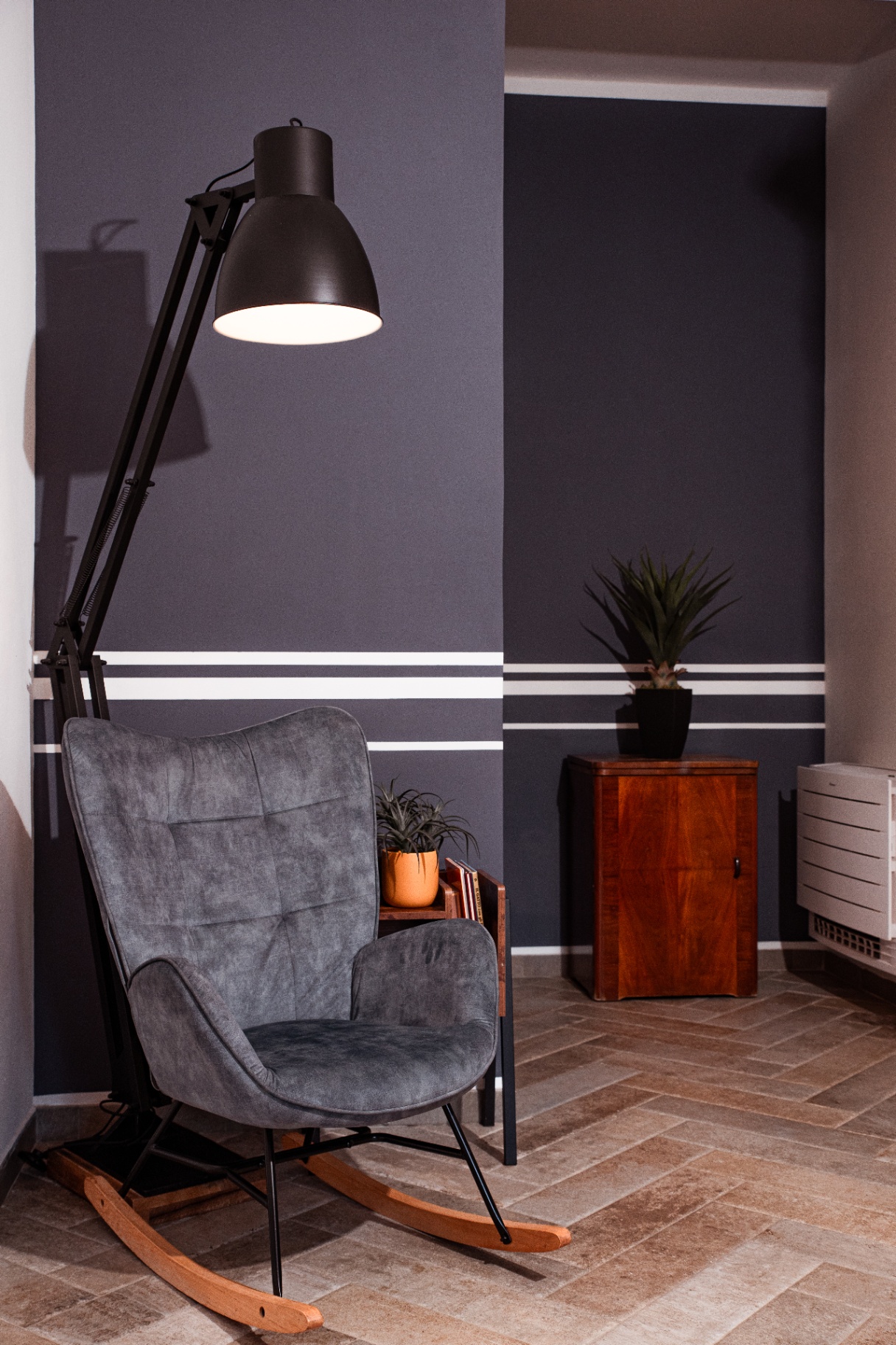 Fauteuil à bascule sous une liseuse d'atelier, mur bleu ardoise