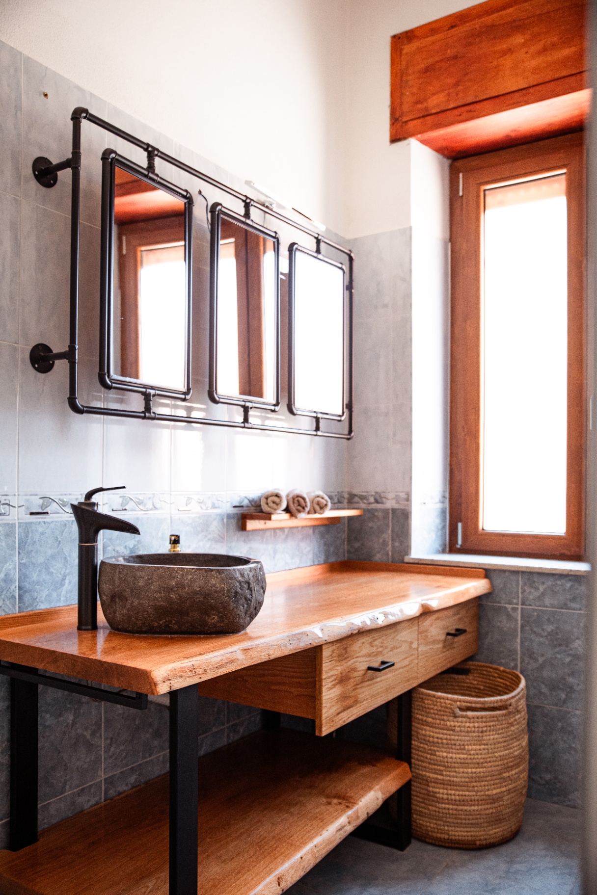 Salle de bain : vasque en galet de rivière sur plan en bois massif à bord naturel et miroirs d'atelier